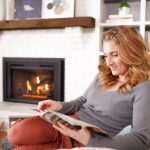 Woman reading a magazine by the fireplace in a cozy living room setting.