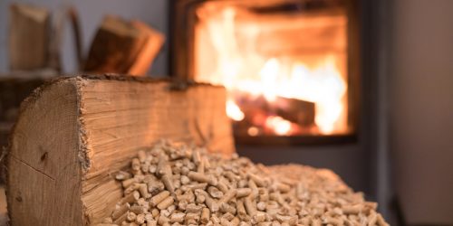 Wood pellets and logs beside a burning fireplace, creating a warm and cozy atmosphere.