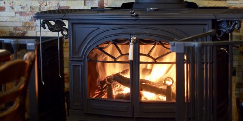 Cozy wood-burning stove with crackling fire, creating a warm and inviting atmosphere in a rustic room.
